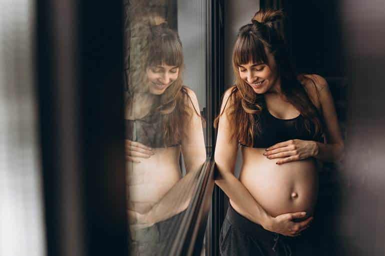 Mulher grávida ao lado da janela